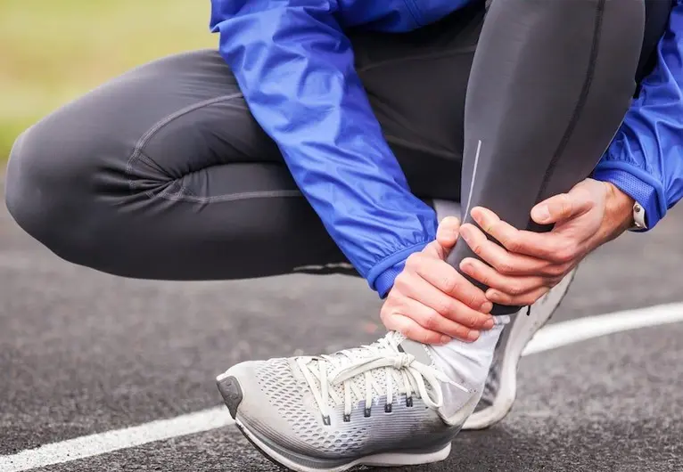 Runner holding an ankle after a sports injury