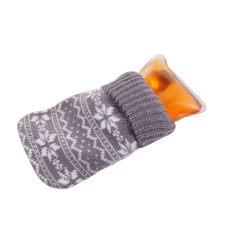 Orange click heat pouch partly inserted in a grey knit cover with a white snowflake pattern