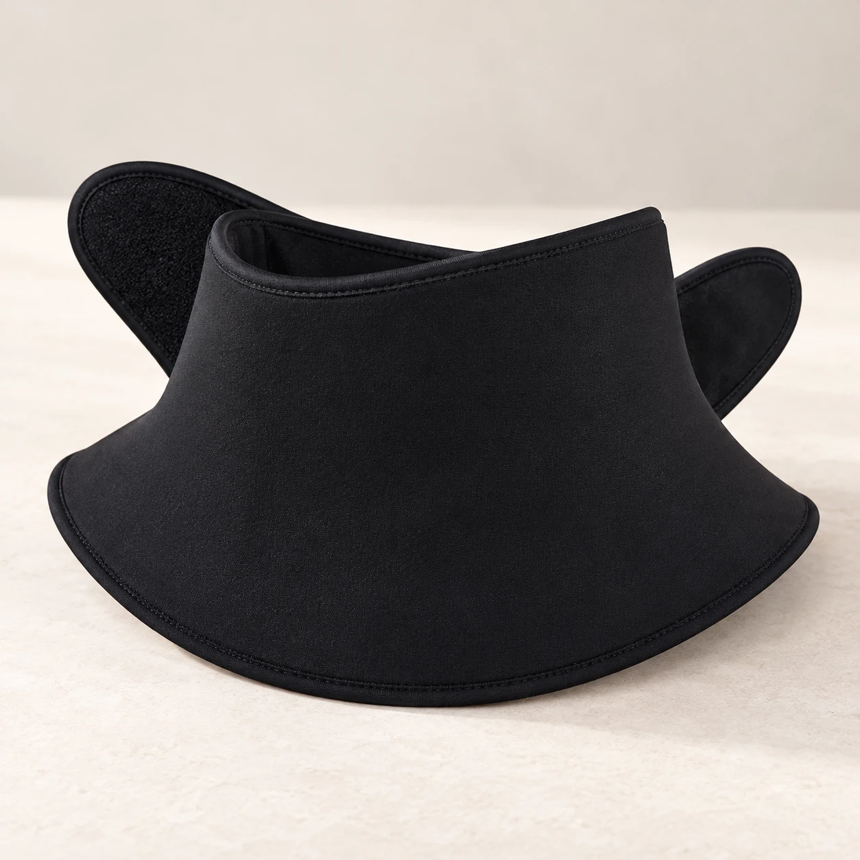 Black flared gel neck collar with overlapping front wings on a neutral surface