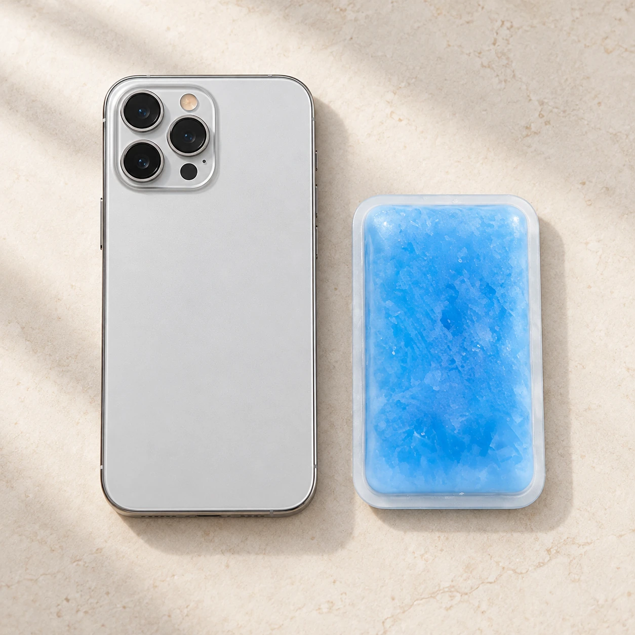 Blue rectangular cooling pack beside an unbranded silver phone